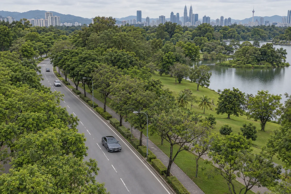 Aerial view of a Mercedes-Benz S-Class driving alone on a tree-lined road beside a park near Kuala Lumpur